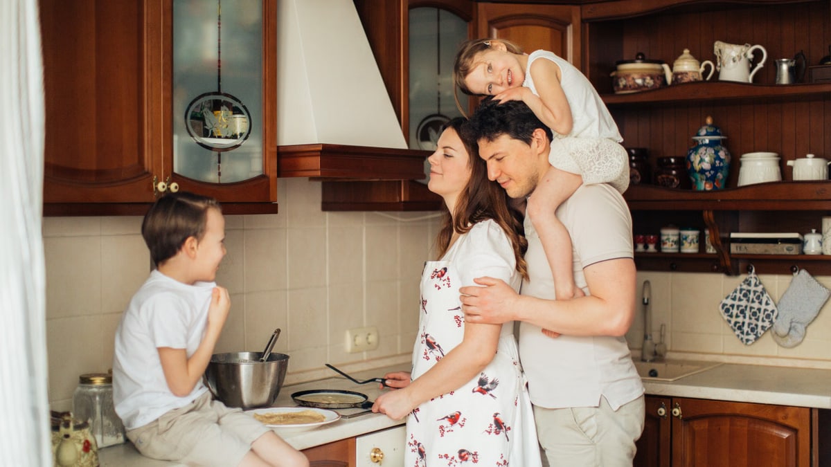 A joyful family moment as parents and children cook together in a cozy kitchen setting.